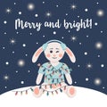 ÃÂ¡ute rabbit in winter headphones is wrapped in a garland. Winter card with shining lights and snow. Merry and bright text